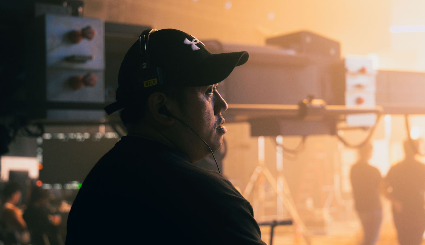 Stage operator at monitors with LED wall glowing behind — mission control during a virtual production shoot