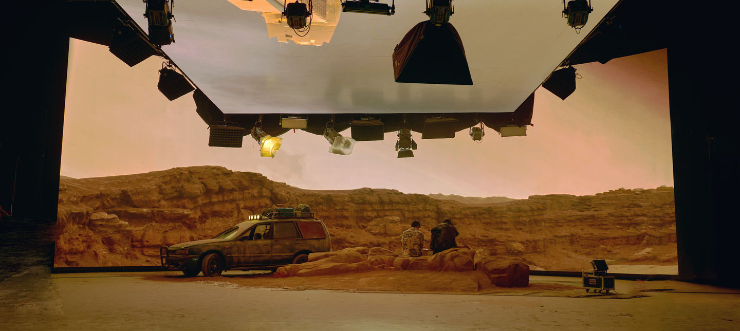 Desert environment displayed on the LED wall with a practical vehicle and rock set pieces in front — overhead LED ceiling visible above